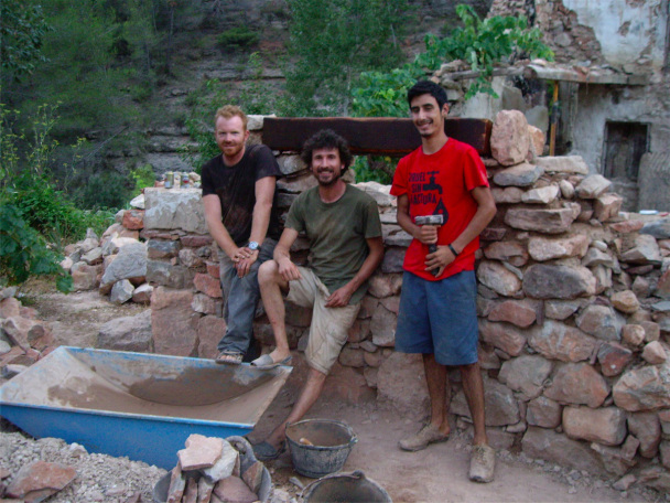 Equipo de Masico Aguilar junto a una pared de piedra en construcción